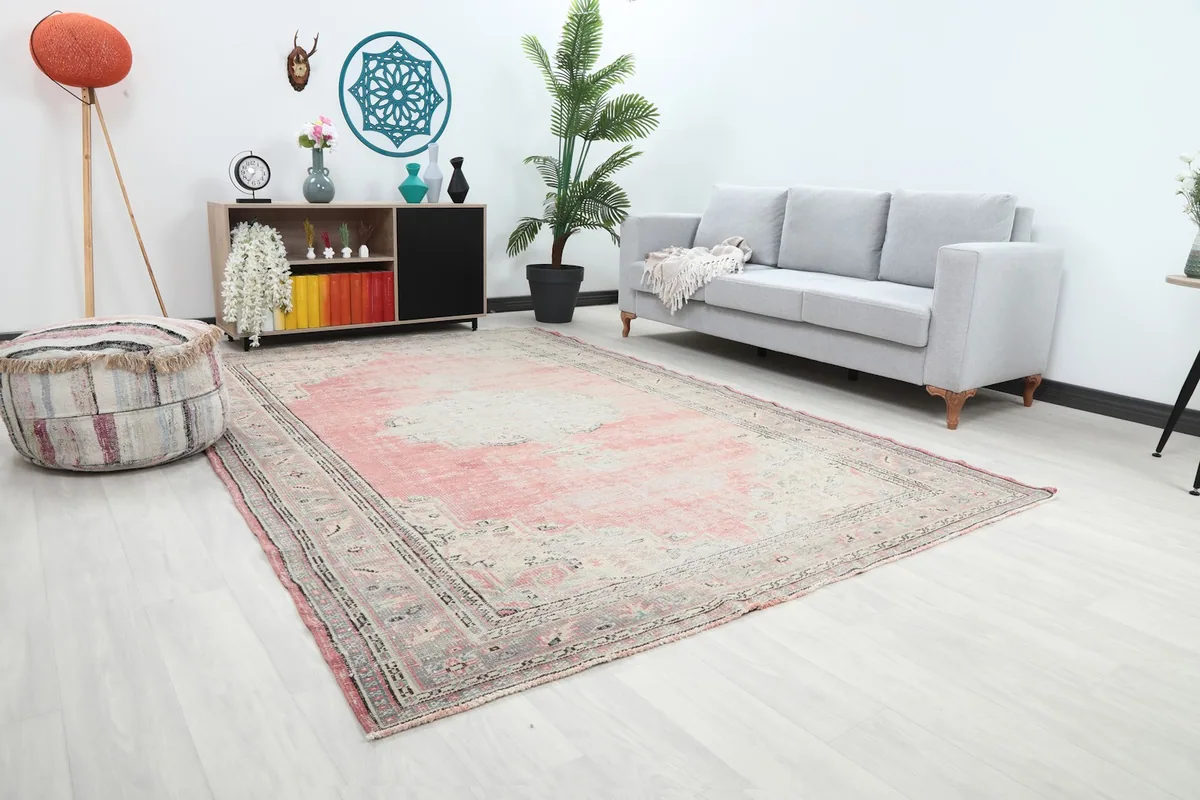 Angle view of the rose and gray rug in a living room, showing its placement relative to a sofa.