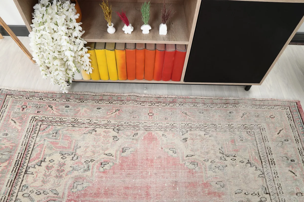 Close-up view of the rug's border design and field from above, near a decorative cabinet.