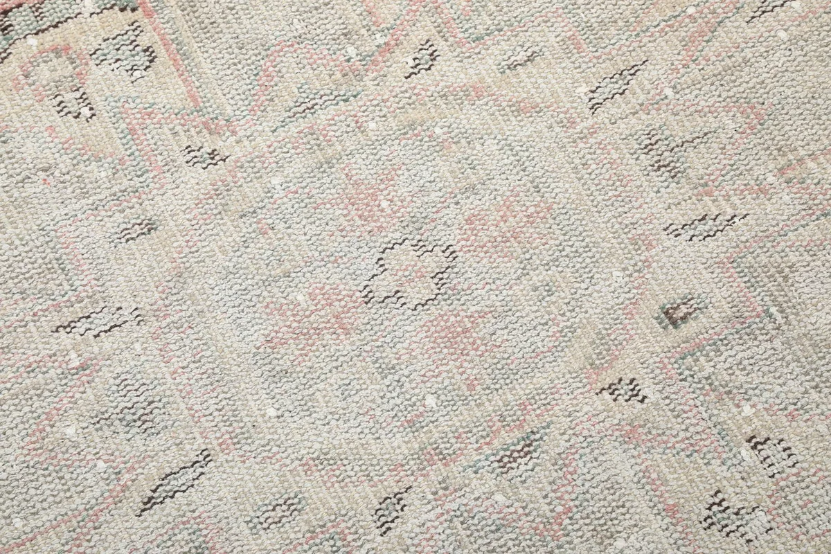 Close-up of the geometric patterns and texture within the beige and gray sections of the rug.