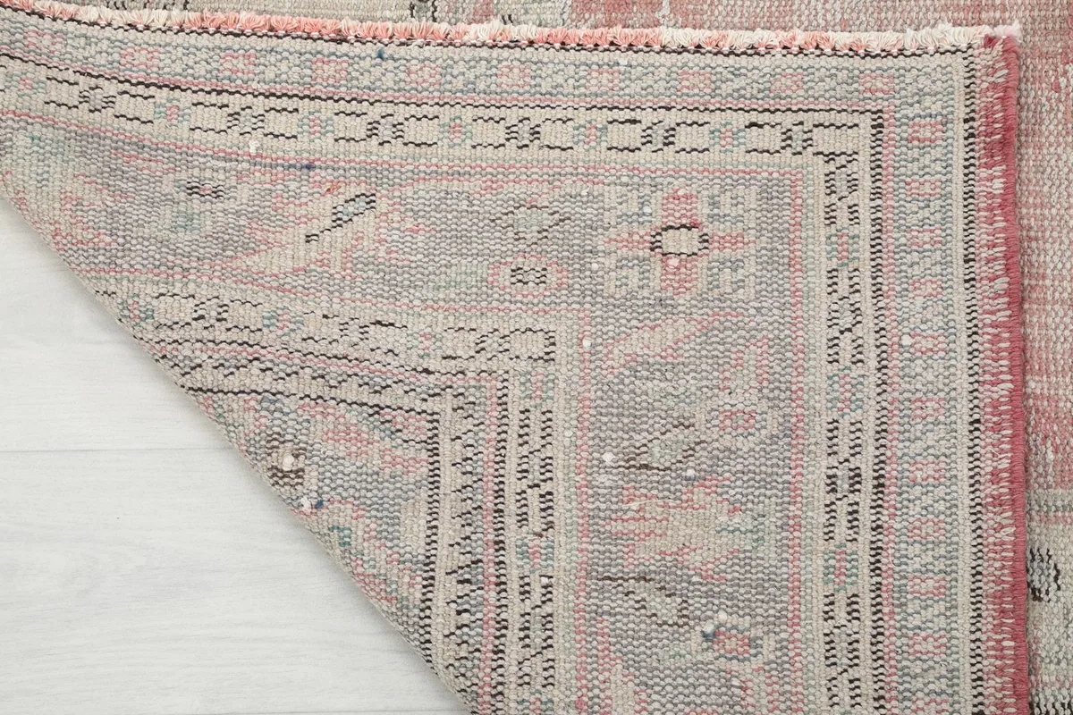View of the back of the rug, revealing the tight hand-knotted cotton foundation and wool pile.