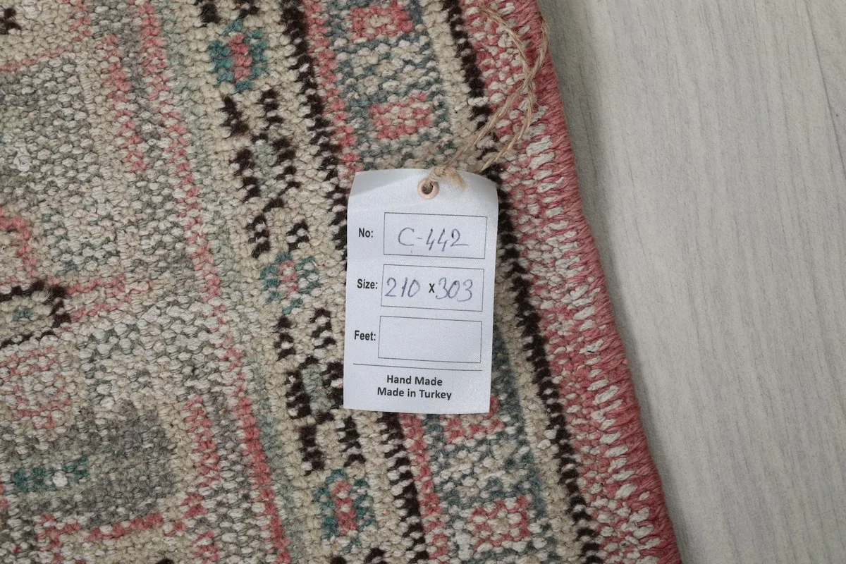 Close-up of the rug's back with a tag showing the dimensions 210 x 303 cm and 'Hand Made in Turkey'.