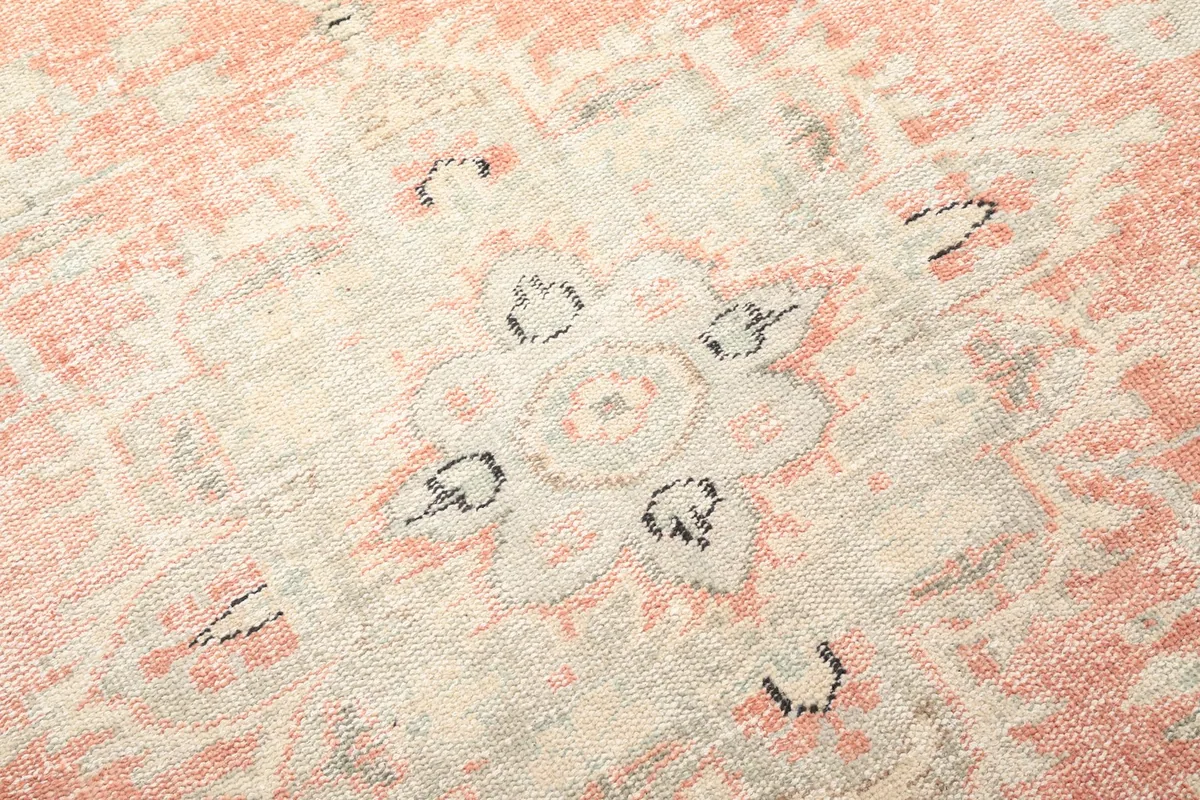 Macro shot showing the low pile texture and intricate hand-knotted details of the rug's central motif