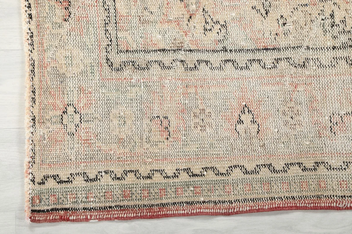 Close-up of the beige border design and the edge of the vintage hand-knotted rug