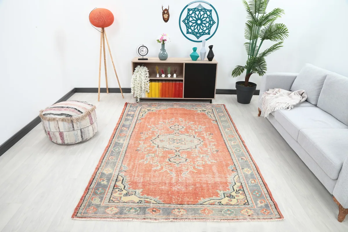 Vintage Anatolian rug displayed in a living room setting with a sofa and decor.