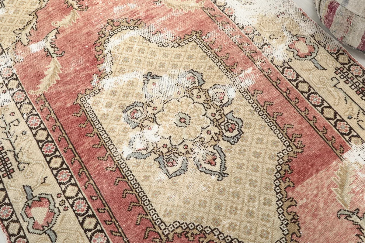 Detailed view of the central medallion, showcasing the geometric and floral motifs in rust, beige, and blue