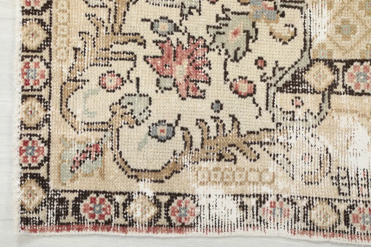 Close-up of the rug's border and corner, showing the black and beige patterns and distressed pile