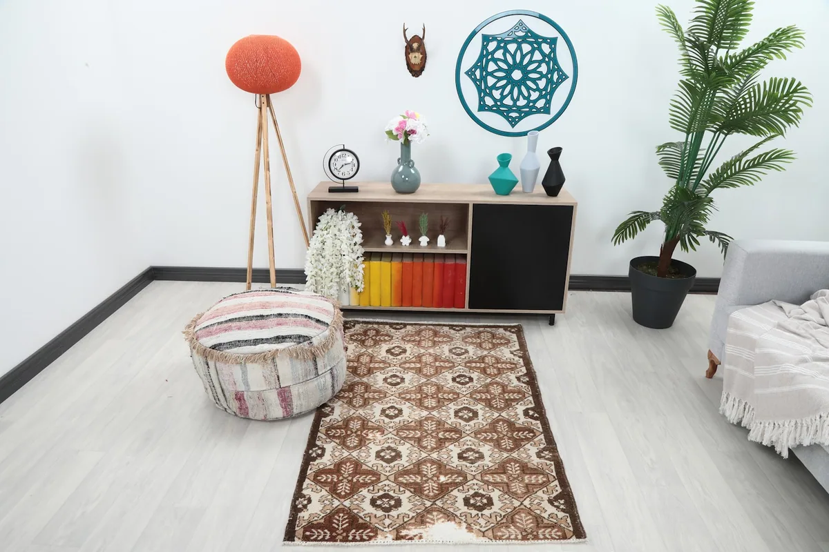 Vintage brown and ivory rug displayed in a room setting with a sofa and plant