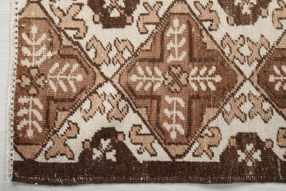 Detailed view of the rug's outer border and corner, showing the brown tones