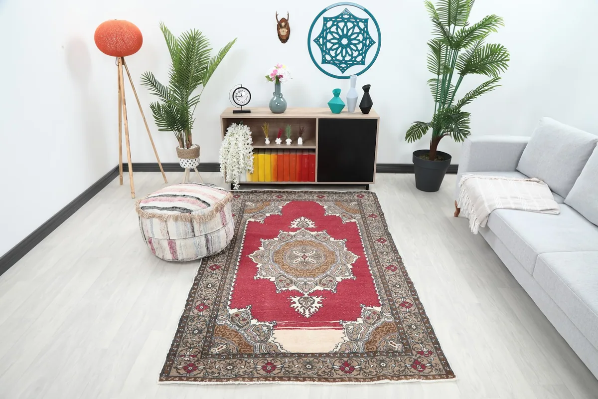 Vintage red rug displayed in a modern living room setting with plants and a sofa