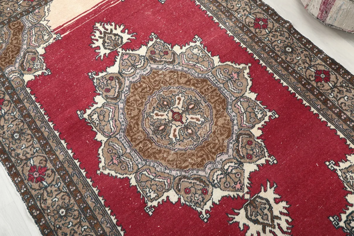 Detailed view of the central medallion and surrounding patterns in red, brown, and ivory
