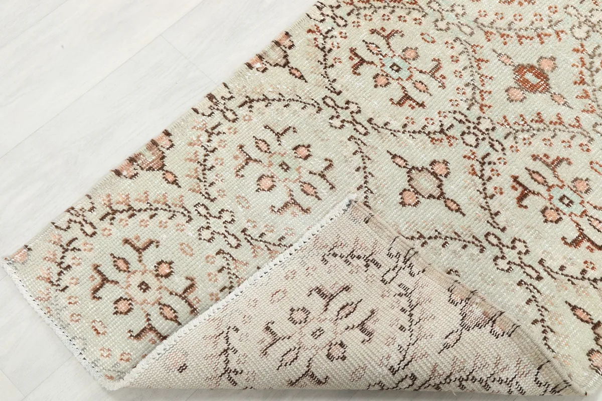 Corner of the rug folded back, revealing the wool pile on cotton foundation and the knotting on the reverse side.