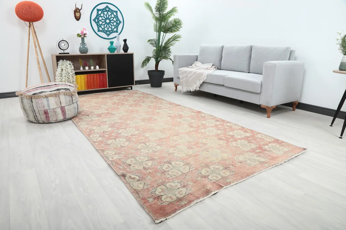 Angle view of the rose geometric vintage rug in a living room setting, showing its long dimensions next to furniture.