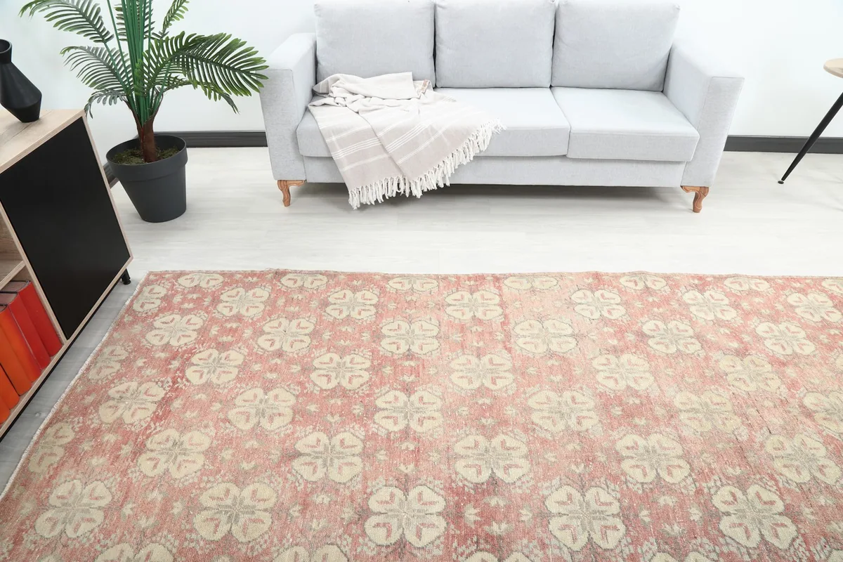 Overhead perspective of the rose geometric rug extending across a room, with a gray sofa in the background.