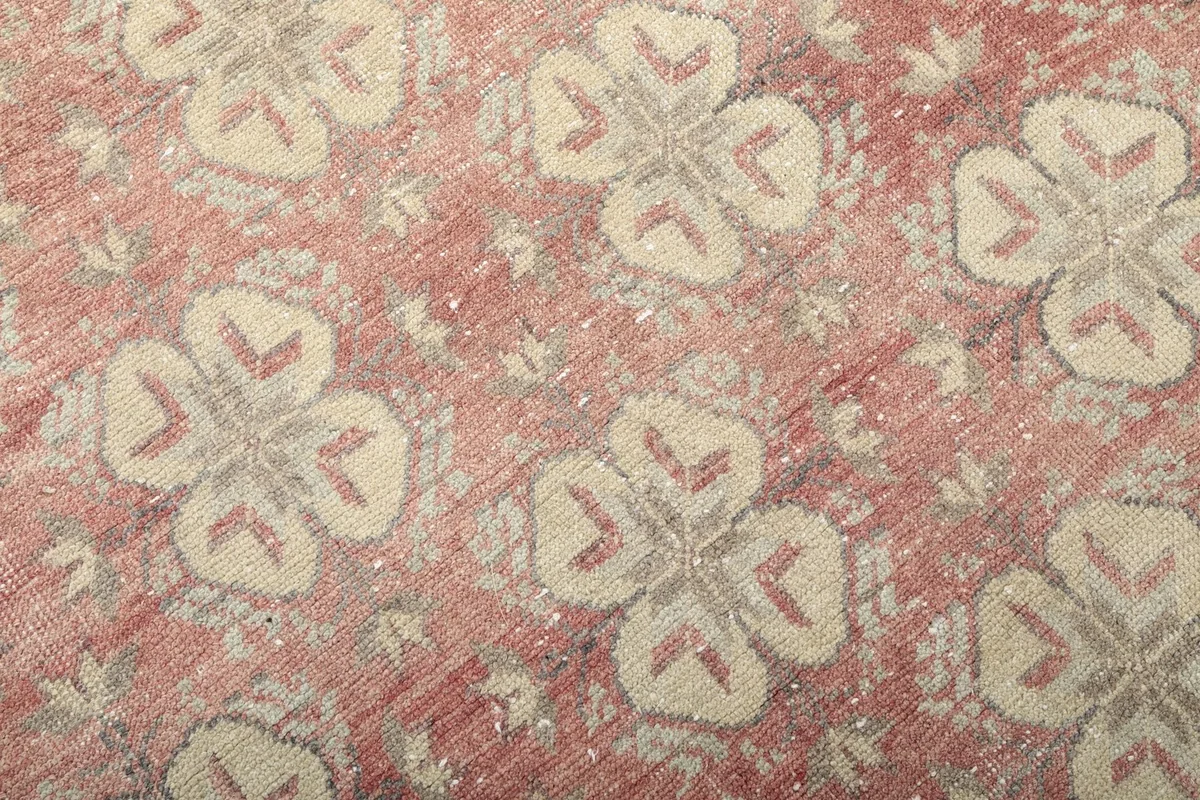 Close-up detail of the rose field and beige geometric motifs with gray accents, revealing the rug's vintage patina.