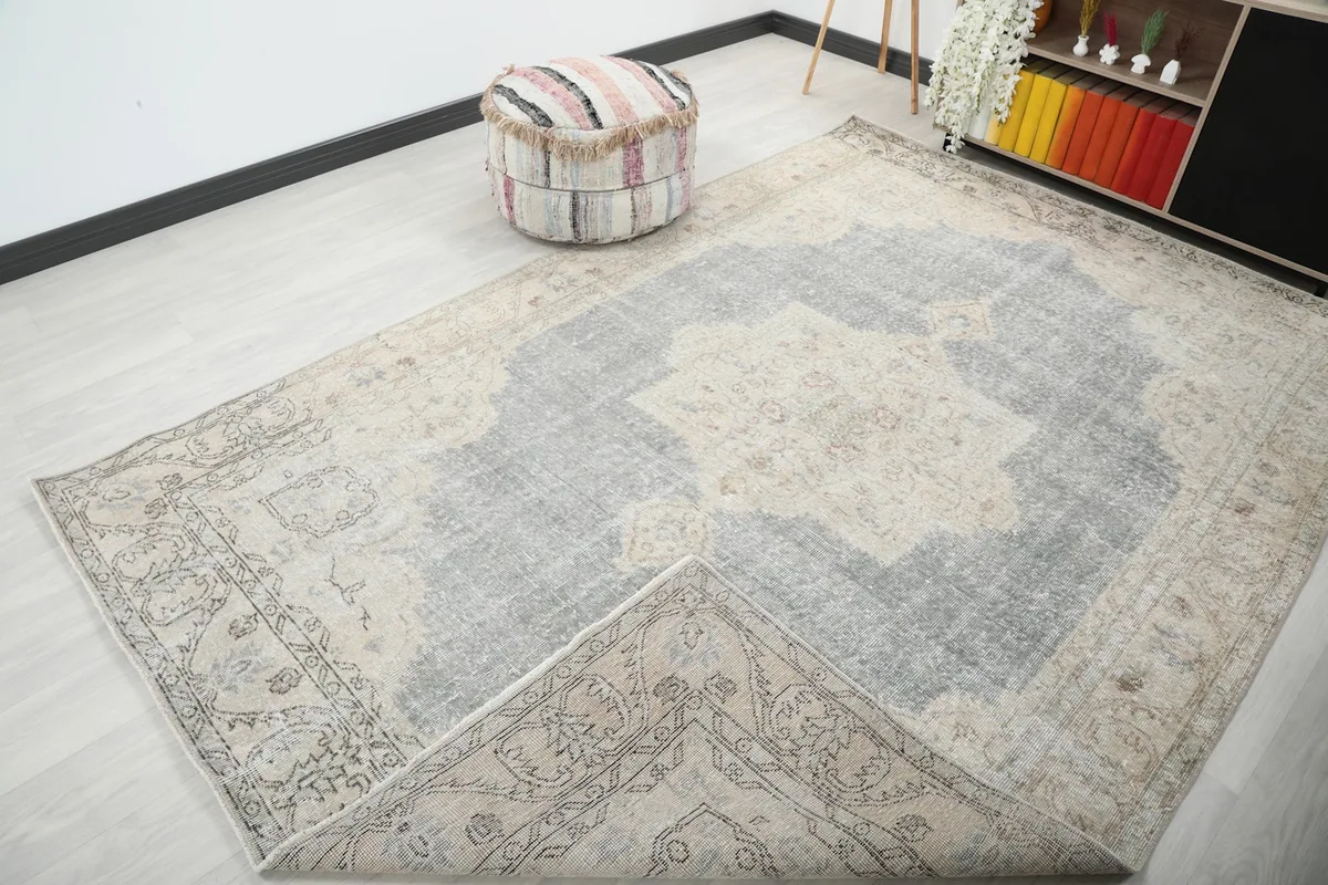The vintage rug with one corner folded back, showing the cotton foundation and overall room view.