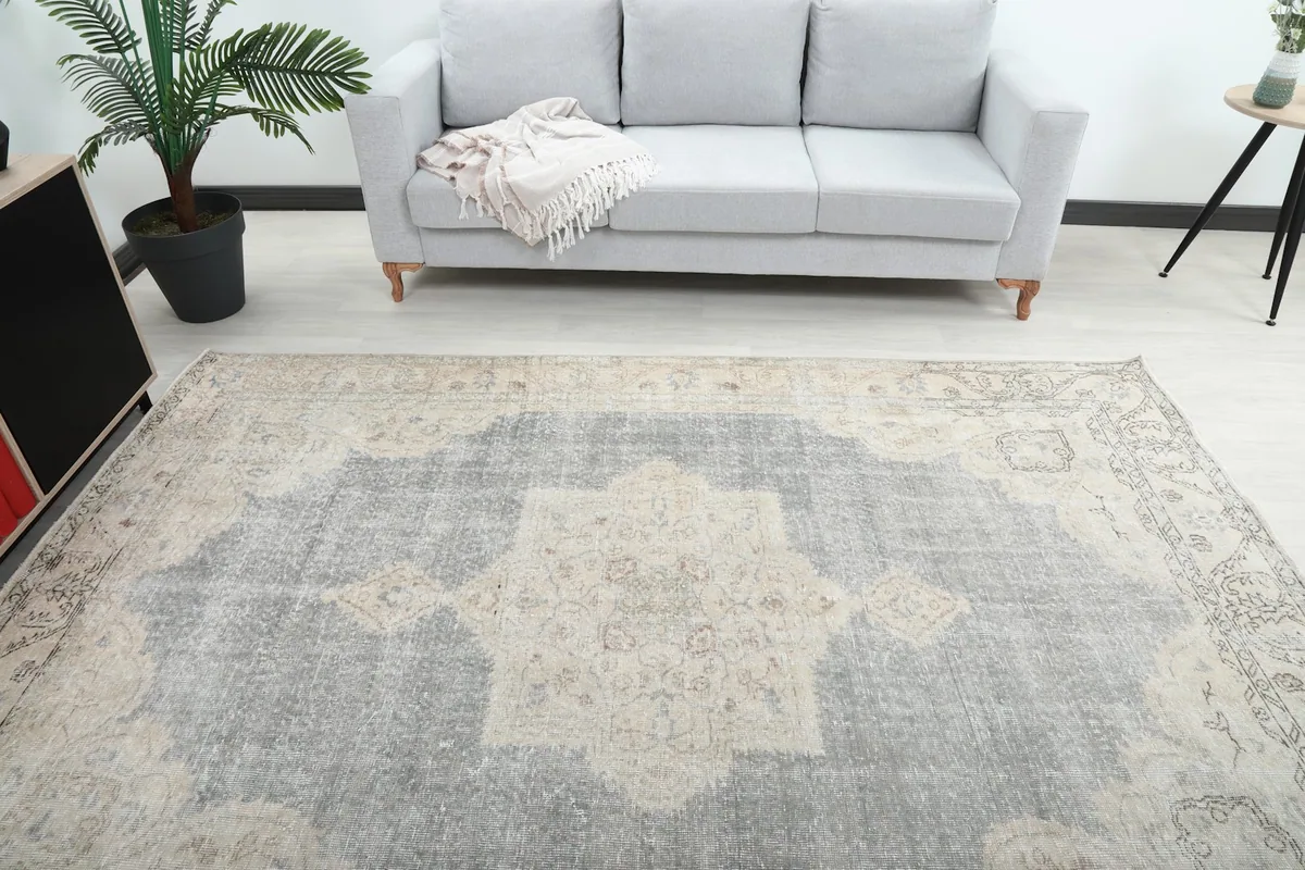 Top-down view of the vintage rug showcasing its central ivory medallion and gray field in a room.