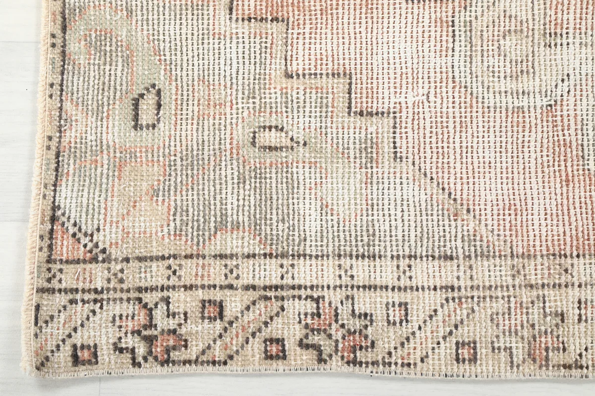 Detail of the Faded Beige Geometric Medallion Runner's border, showing the tribal motifs and colors.