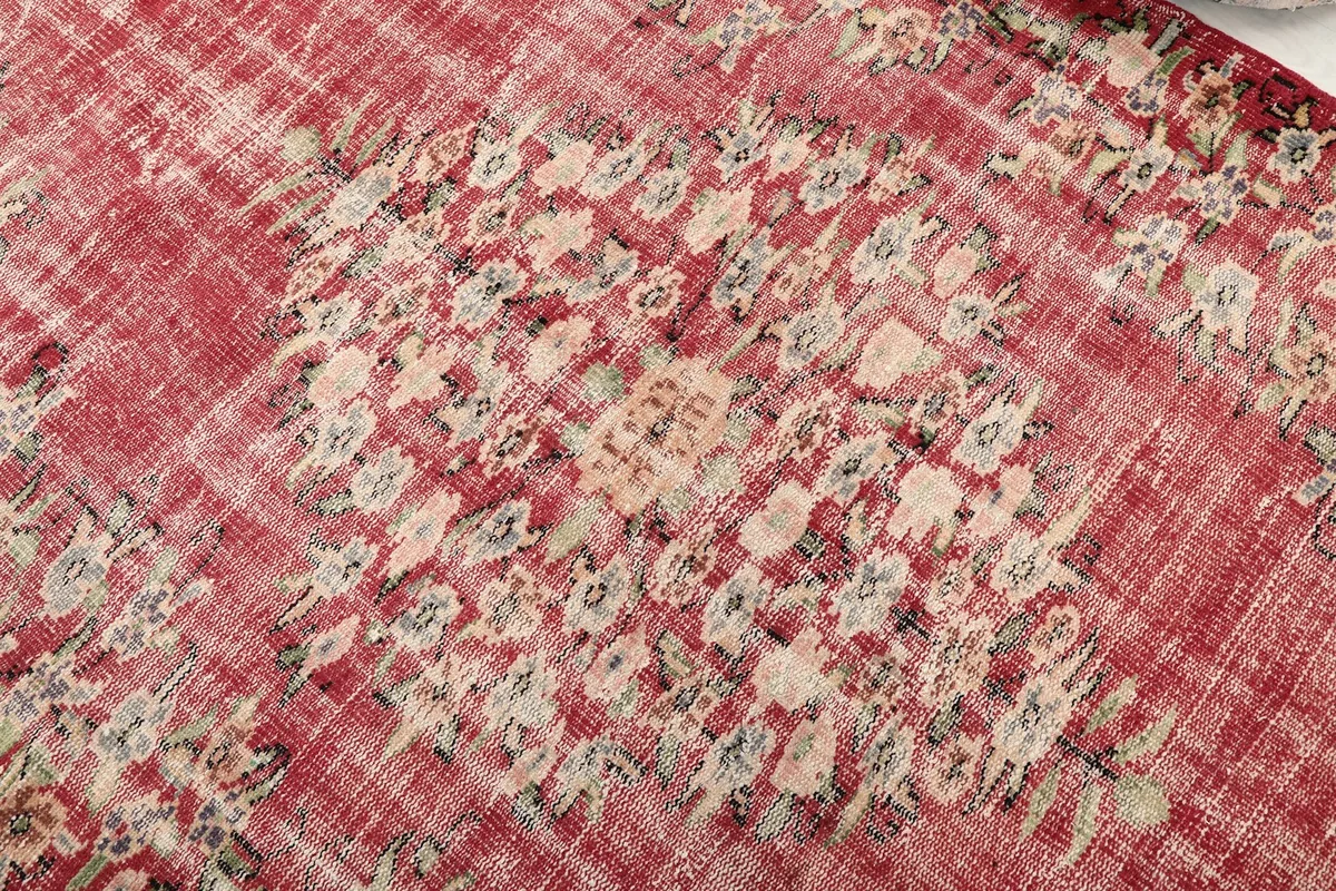 Close-up detail of the central floral and geometric motifs on the red vintage rug, showing texture