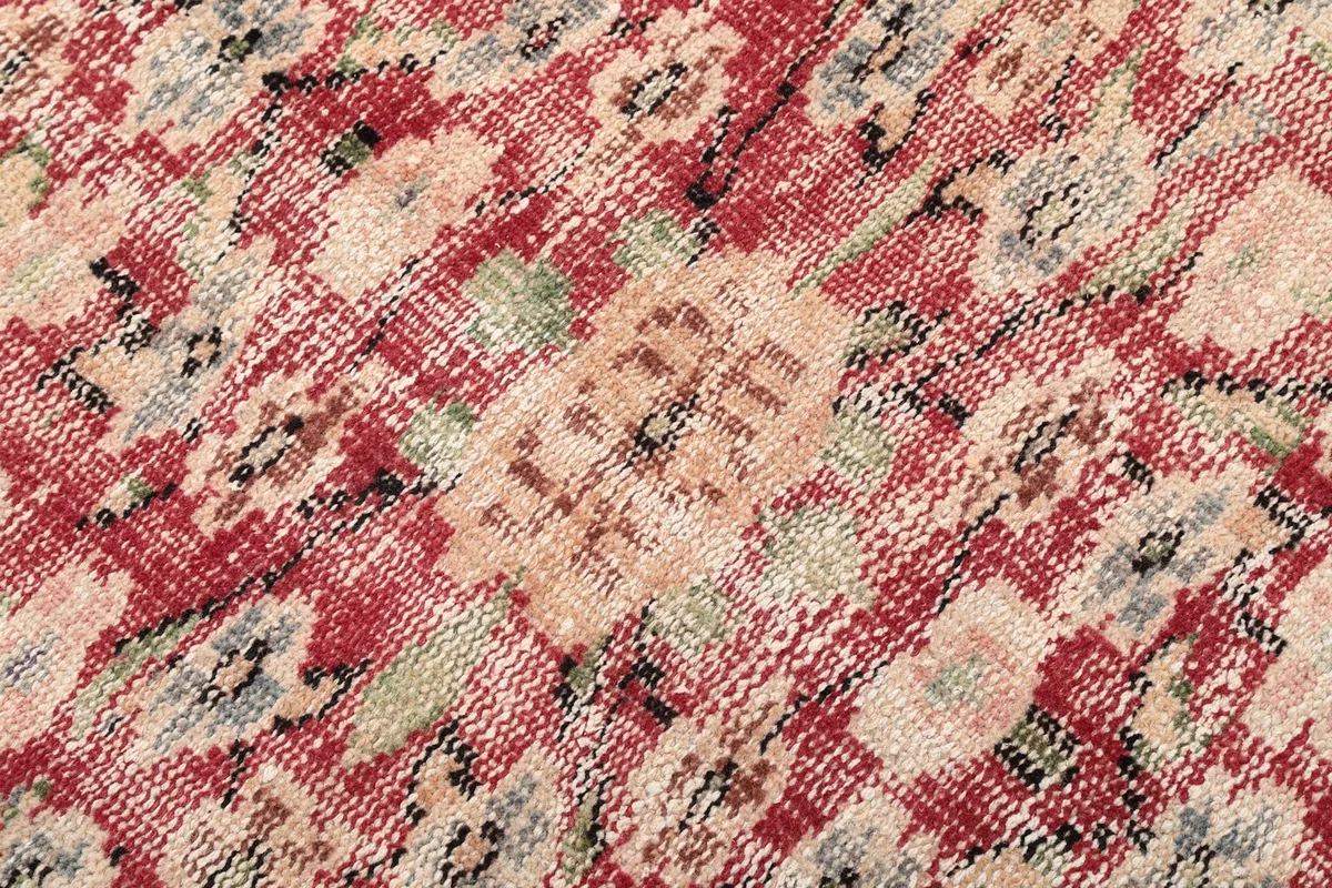 Macro detail of the hand-knotted wool pile and intricate patterns in red, beige, and gray