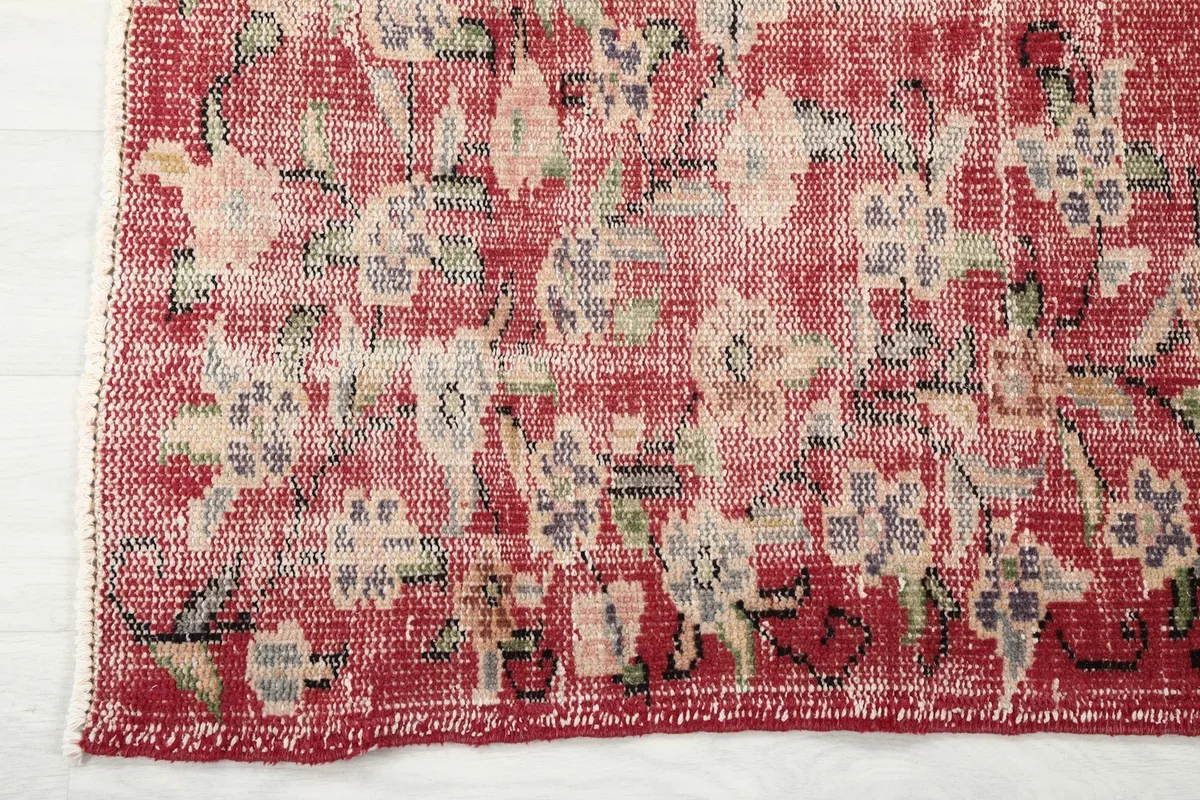 Close-up of the rug's edge, showing the distressed floral border and fringe