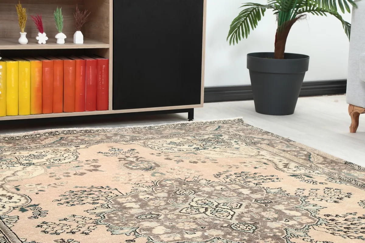 Close-up angled view of the rose field and brown border of the vintage area rug