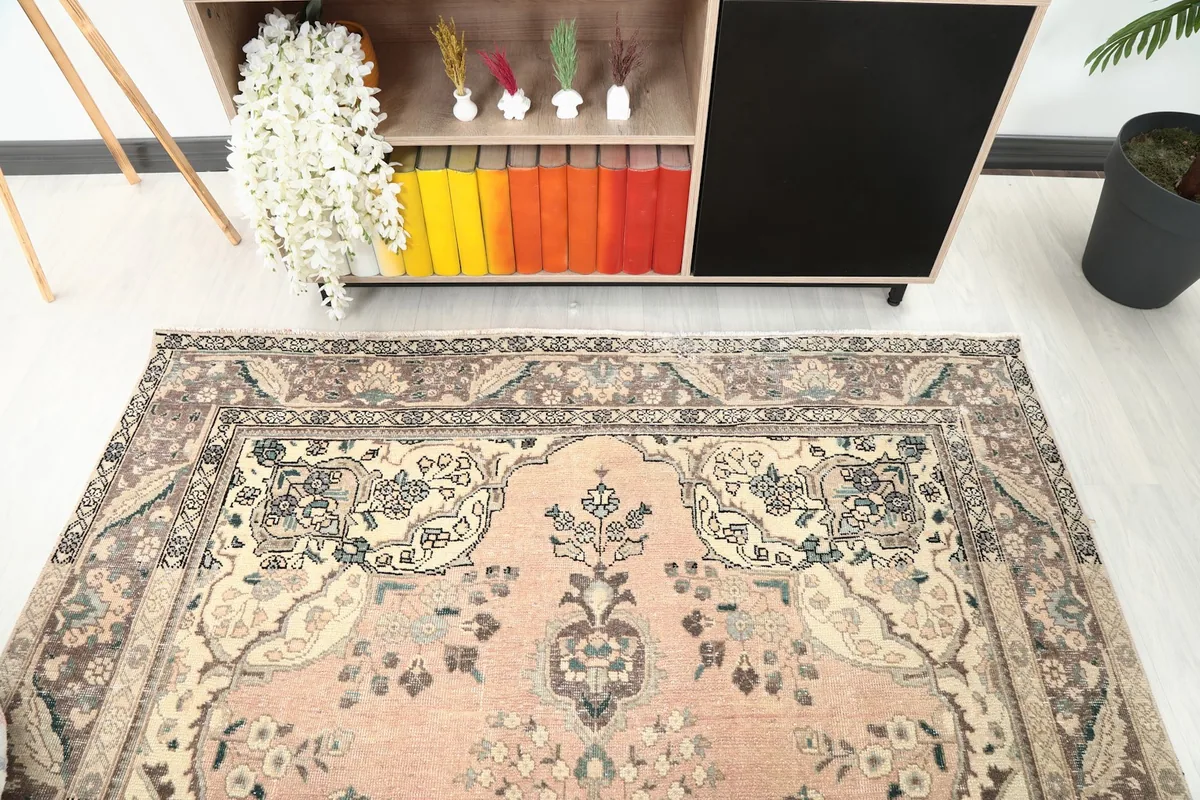 Angled view of the rose and brown rug, highlighting the upper section and border details