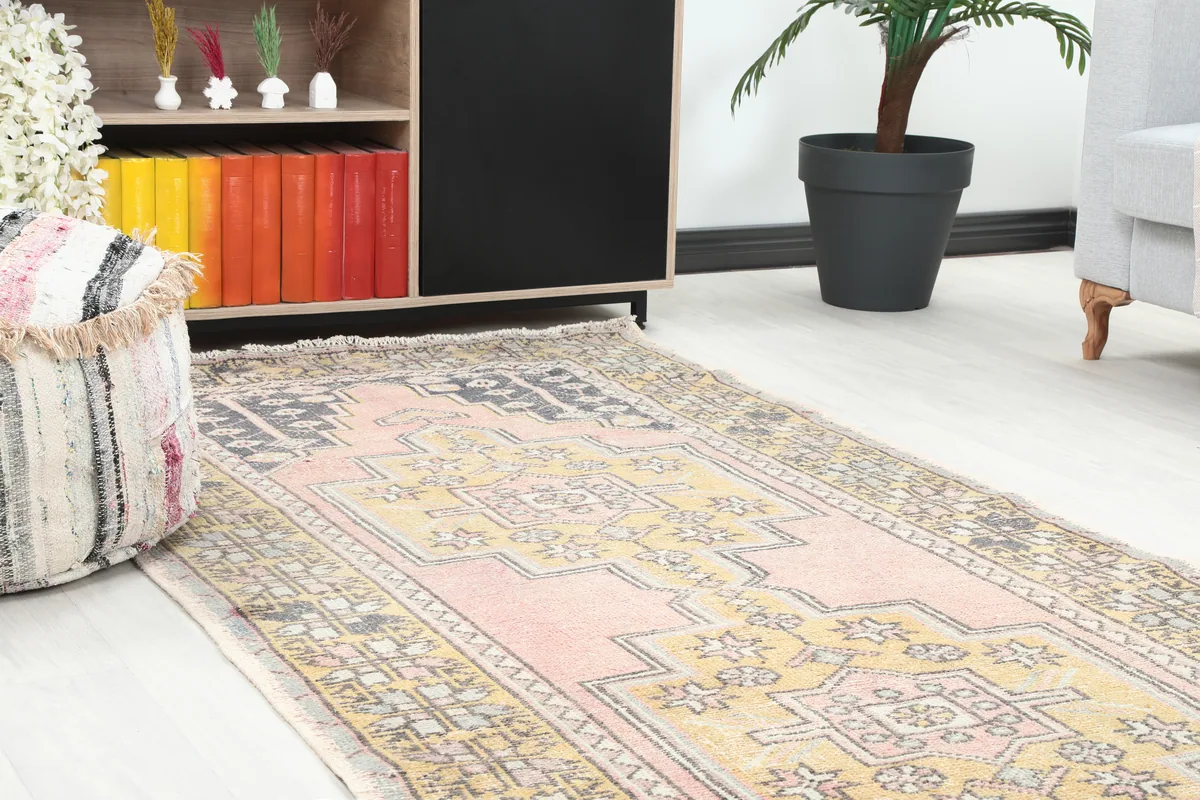 Angled view of the Pink Gold Geometric Anatolian Rug, showing the faded pink and gold tones and geometric motifs.