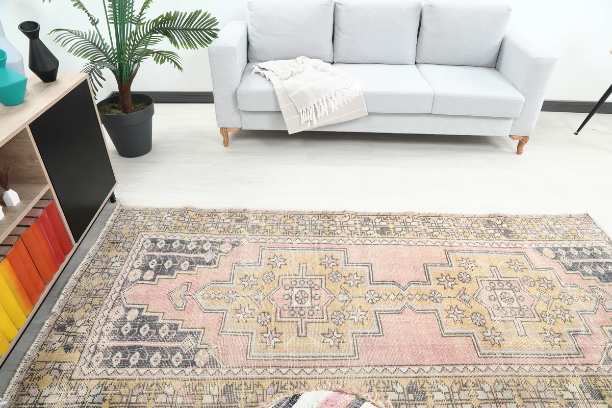 Overhead view of the Pink Gold Geometric Anatolian Rug in a room, emphasizing its full pattern and colors.