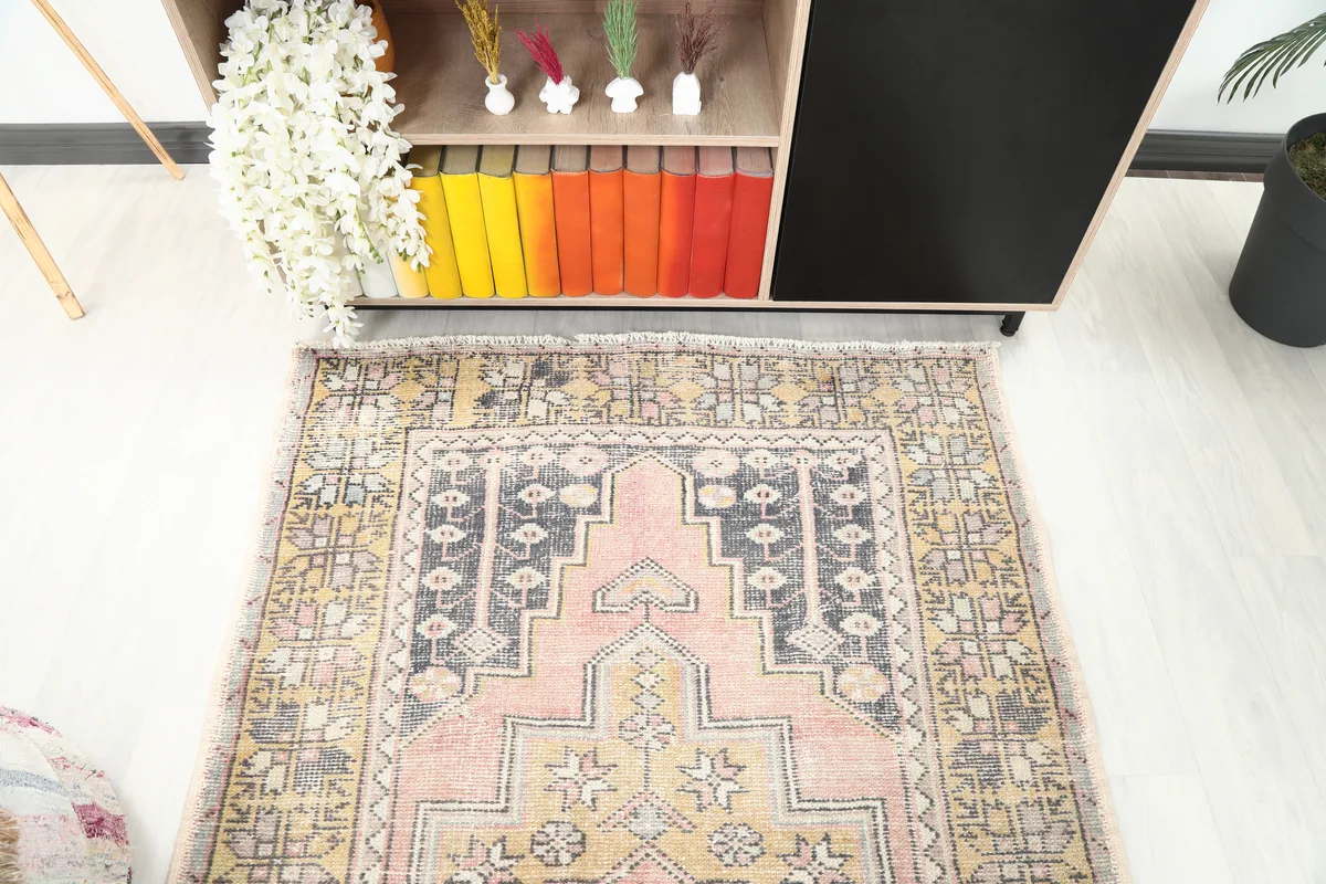 Close-up room view of one end of the Pink Gold Geometric Anatolian Rug, showing pattern details and colors.