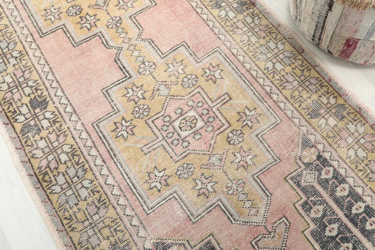 Detail shot of the central geometric medallion and surrounding patterns on the Pink Gold Geometric Anatolian Rug.