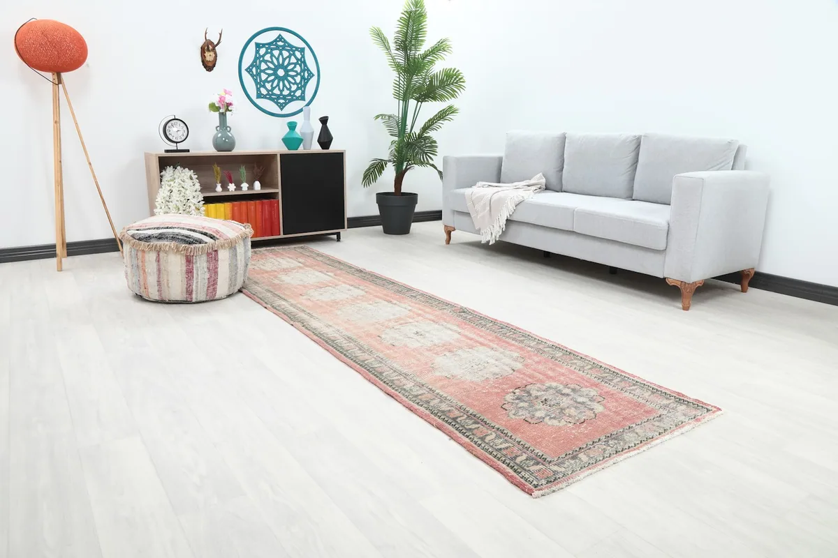 Angle view of the rose runner extending through a living space with a striped ottoman