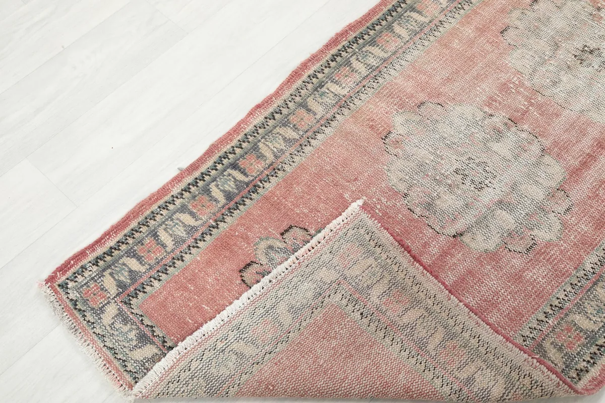View of the low pile texture and the cotton foundation where a corner of the rug is folded back