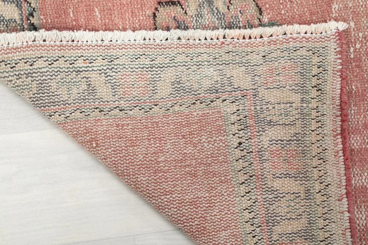 Underside view of the hand-knotted cotton foundation and the reverse of the rose wool pile