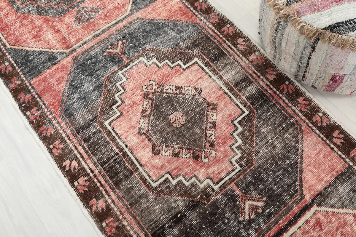 Detailed view of the central geometric medallion pattern in rose and charcoal with ivory accents.