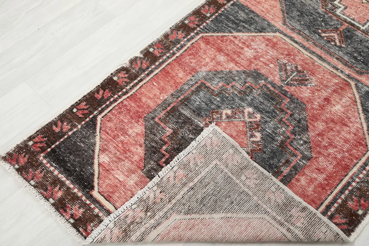 Corner of the runner rug folded back, showing the wool pile on cotton foundation.