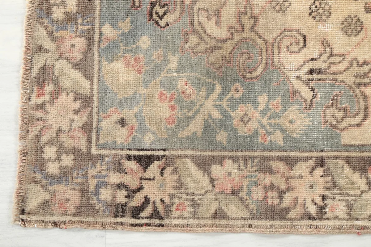 Close-up of the border design showing brown, beige, and blue tones with floral details