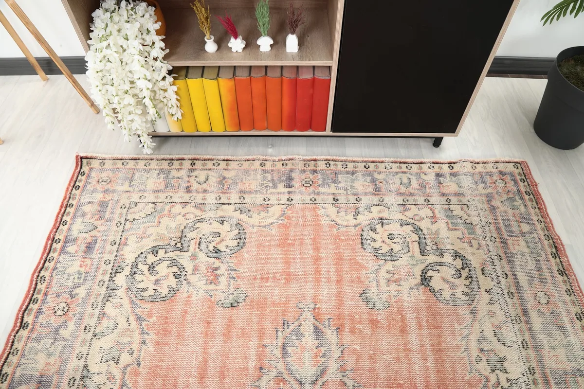 View of the rug's upper section, showing the intricate border design and the faded rust field in a room setting.