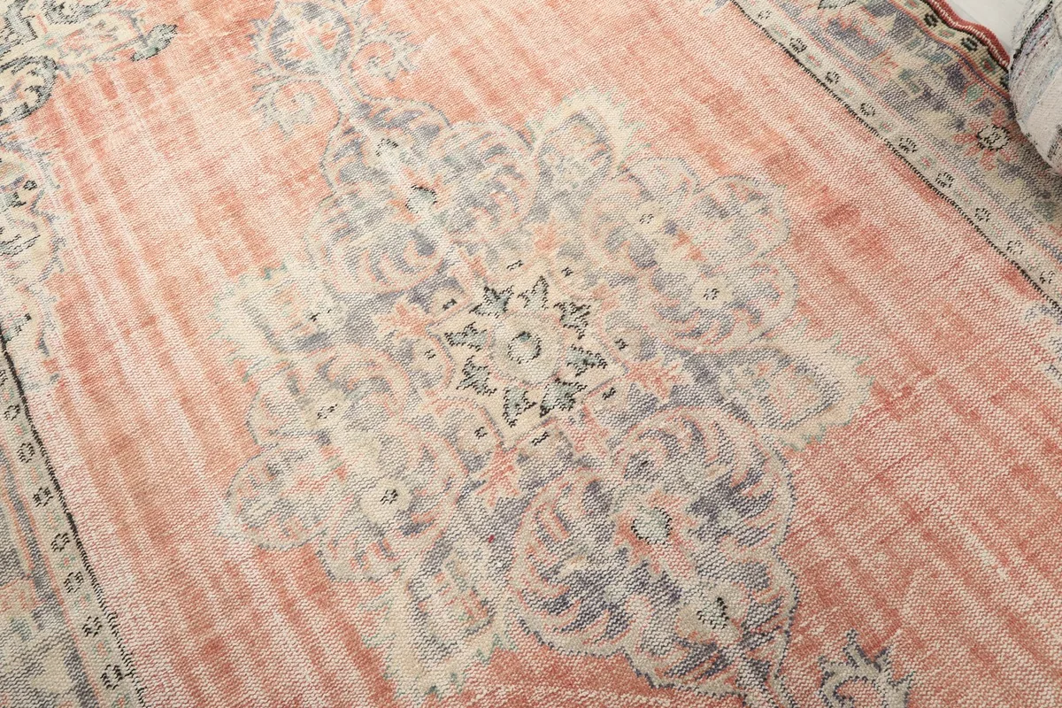 Detailed view of the central medallion and surrounding motifs in cream, blue, and rust tones, showing wool pile texture.