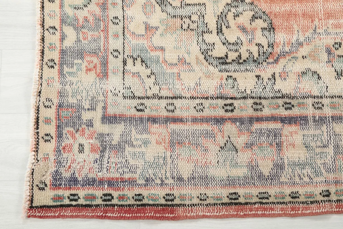 Detailed shot of the rug's border, showcasing geometric patterns in blue, beige, and rust, and the finished edge.