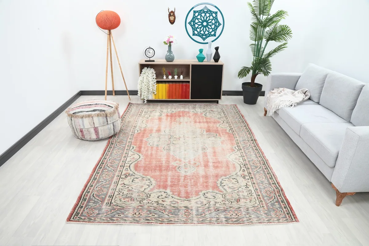 Rose and ivory vintage rug in a living room setting with a gray sofa and modern decor