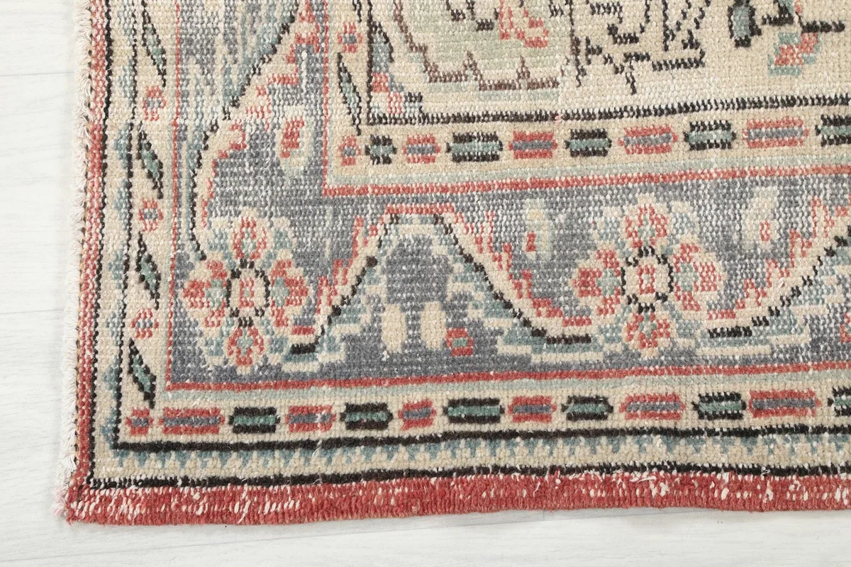 Corner detail of the rug showing the gray, rose, and black border patterns