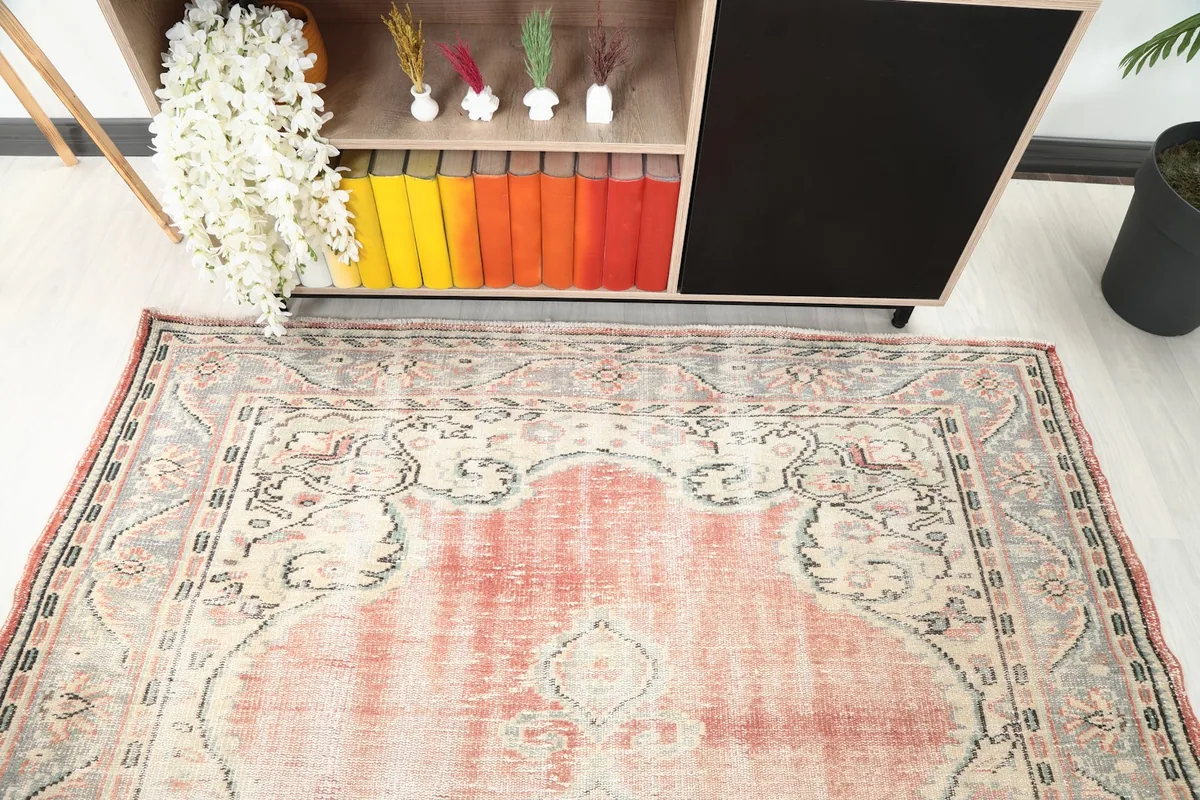 Overhead view of the top portion of the rose and ivory vintage rug, showing the border