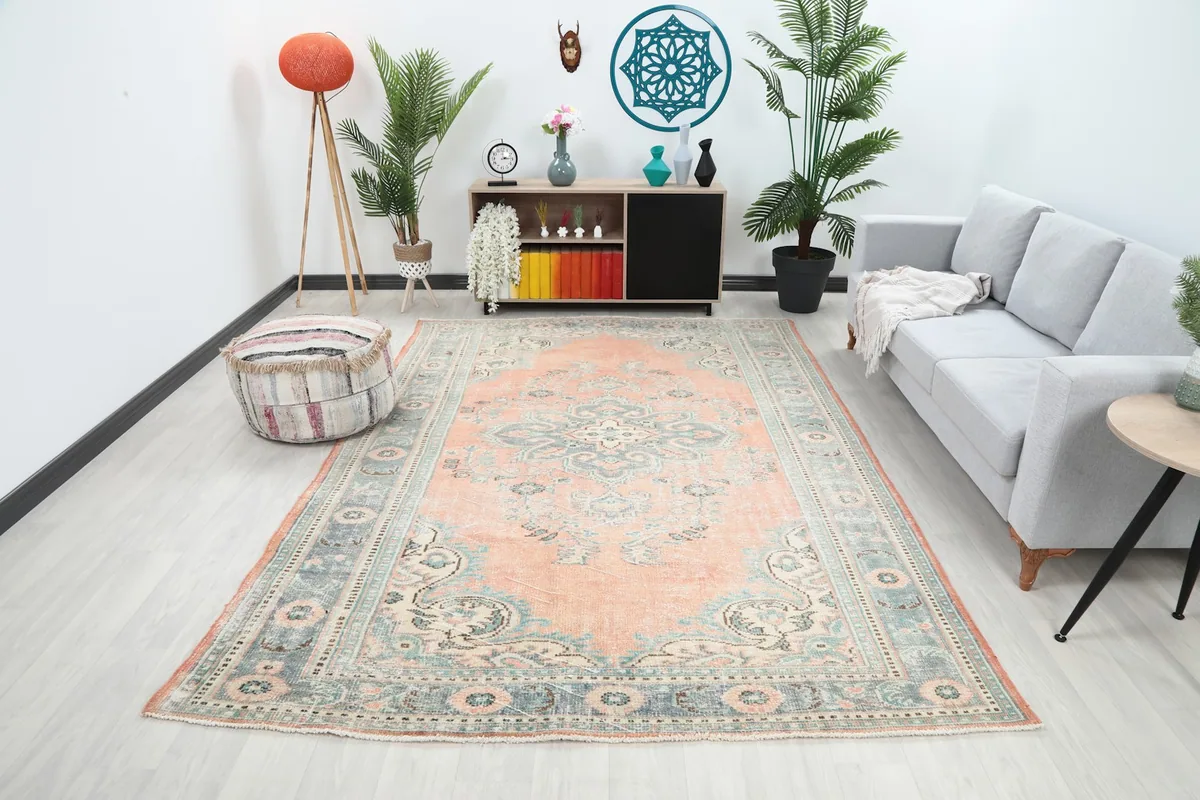 Large vintage rug in a living room setting with a gray sofa and various plants