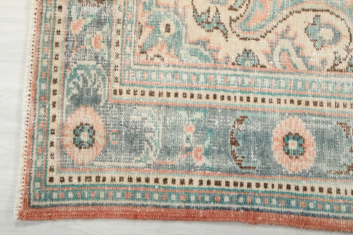 Detailed view of the blue and gray border design with rose elements on the vintage rug
