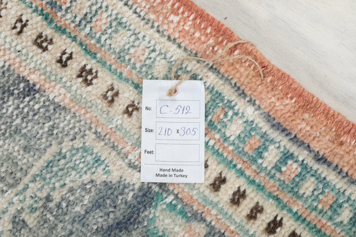 Corner of the rug with a tag displaying its size 210 x 305 cm and 'Hand Made in Turkey'