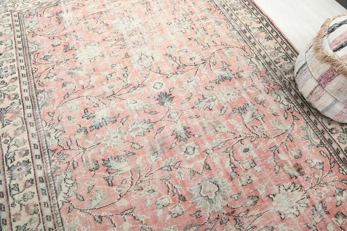Angled detail shot of the rug's surface, revealing the subtle variations in the rose and ivory colors and texture.