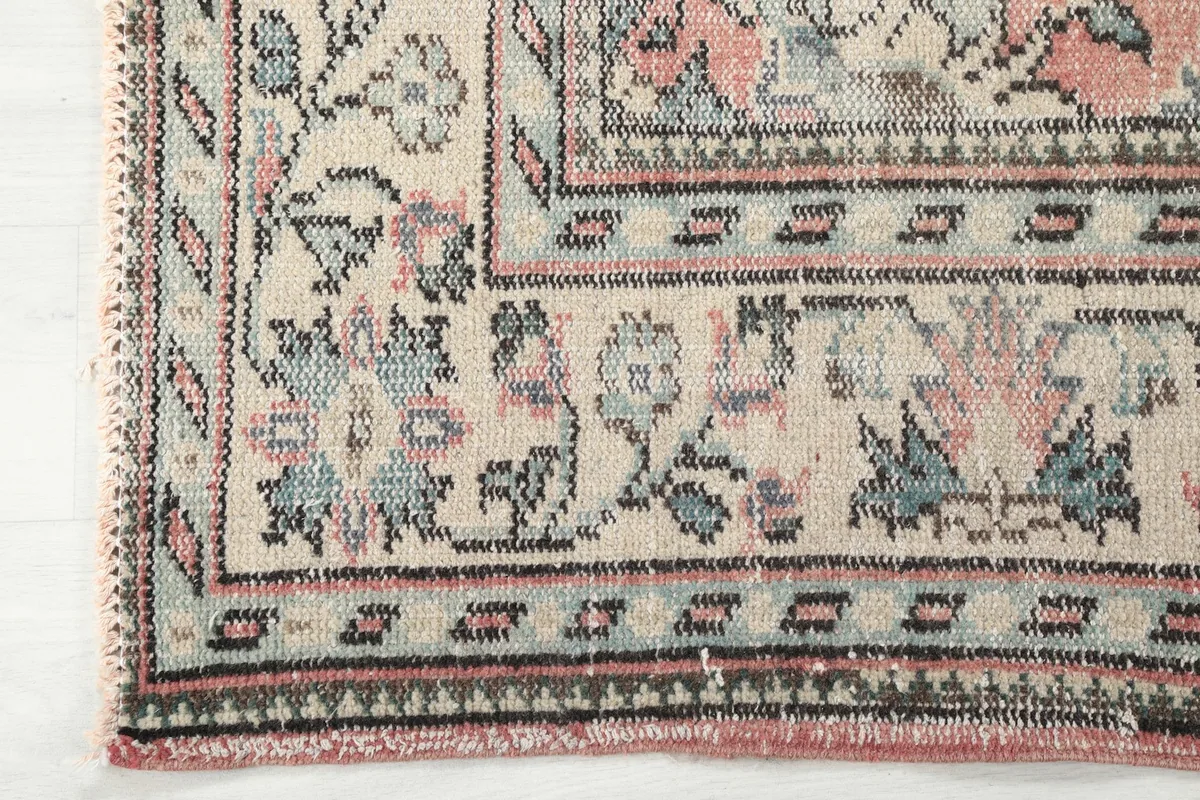 Detailed close-up of the rug's intricate border, featuring geometric and floral elements in ivory, blue, and gray.