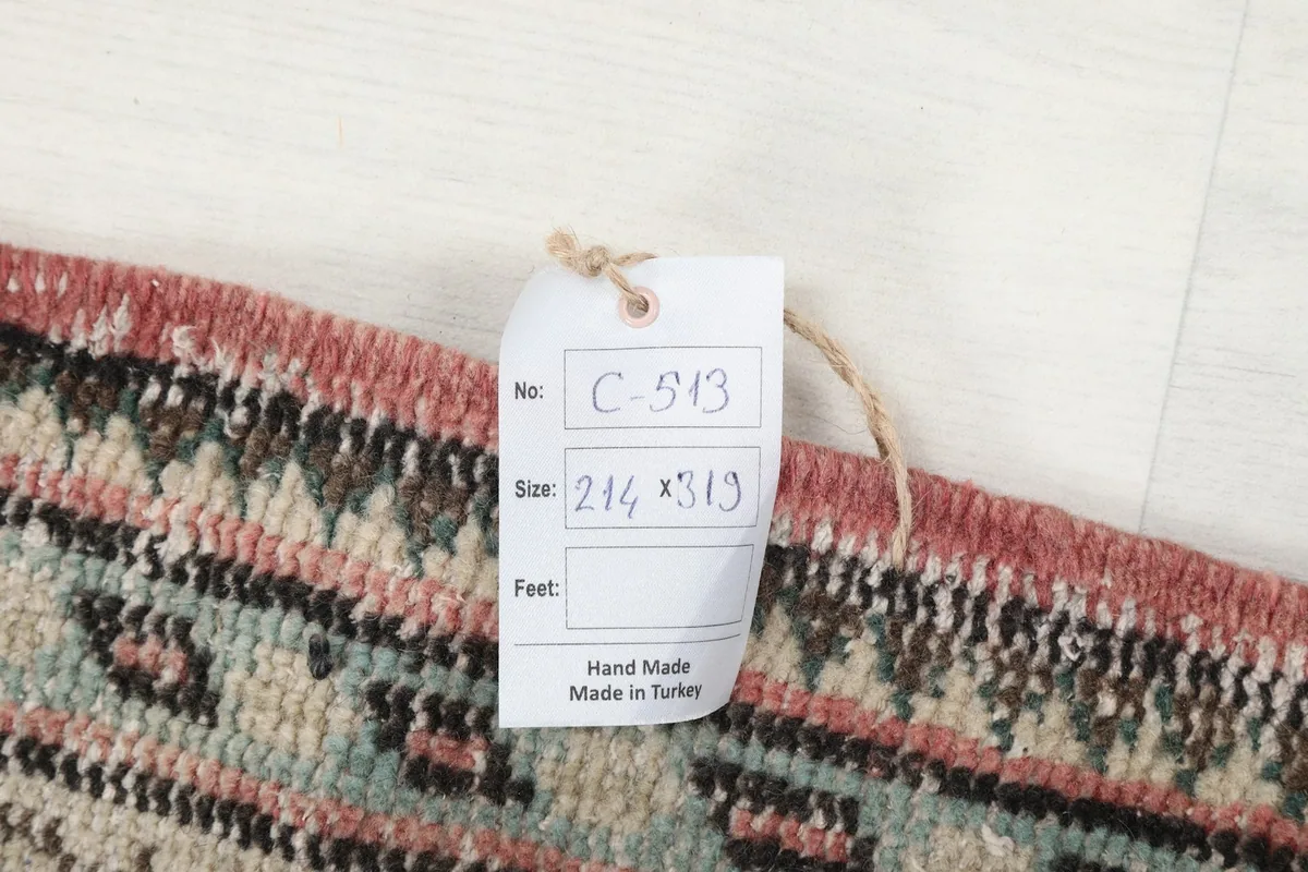Detail of the rug's edge with a product tag showing the dimensions 214 x 319 cm and 'Hand Made in Turkey'.