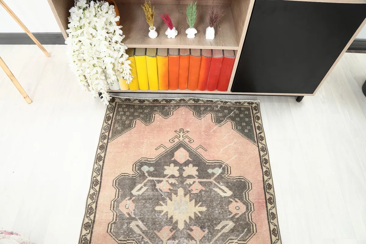 Close-up view of one end of the runner rug, focusing on the charcoal medallion and rose field