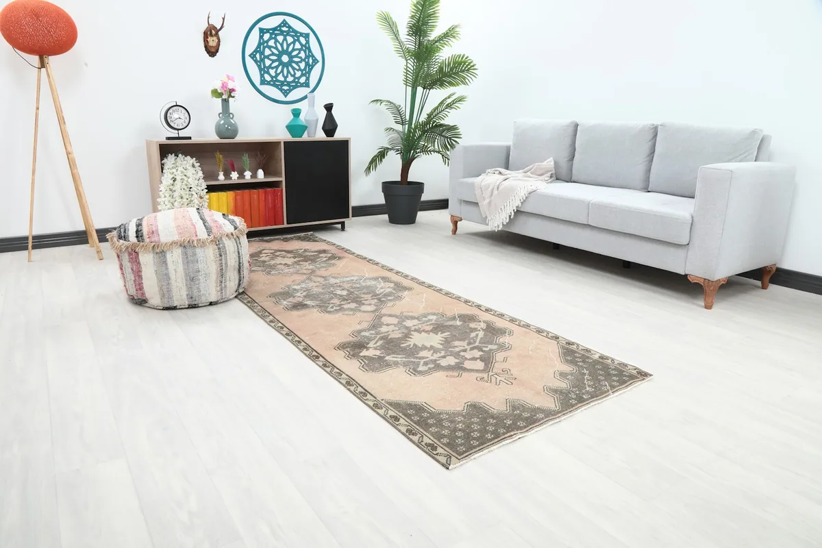 Runner rug from an angle in a room, highlighting the distressed rose field and charcoal border